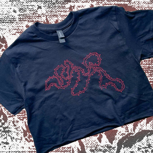 Black cropped t-shirt with red thorny abstract line design, featuring a minimalist edgy graphic across the chest.