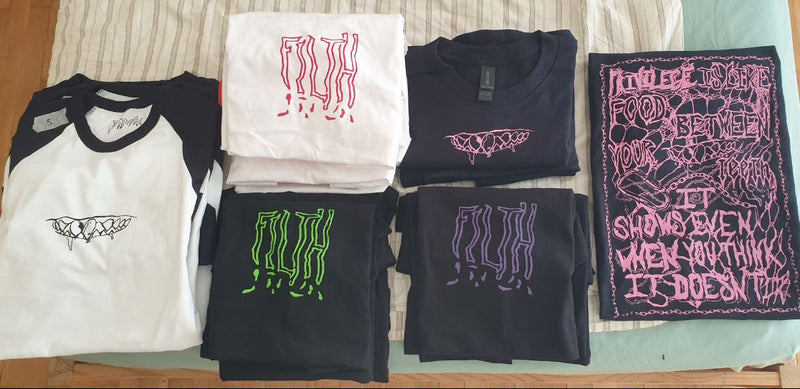 Collection of t-shirts with various designs on a wooden surface