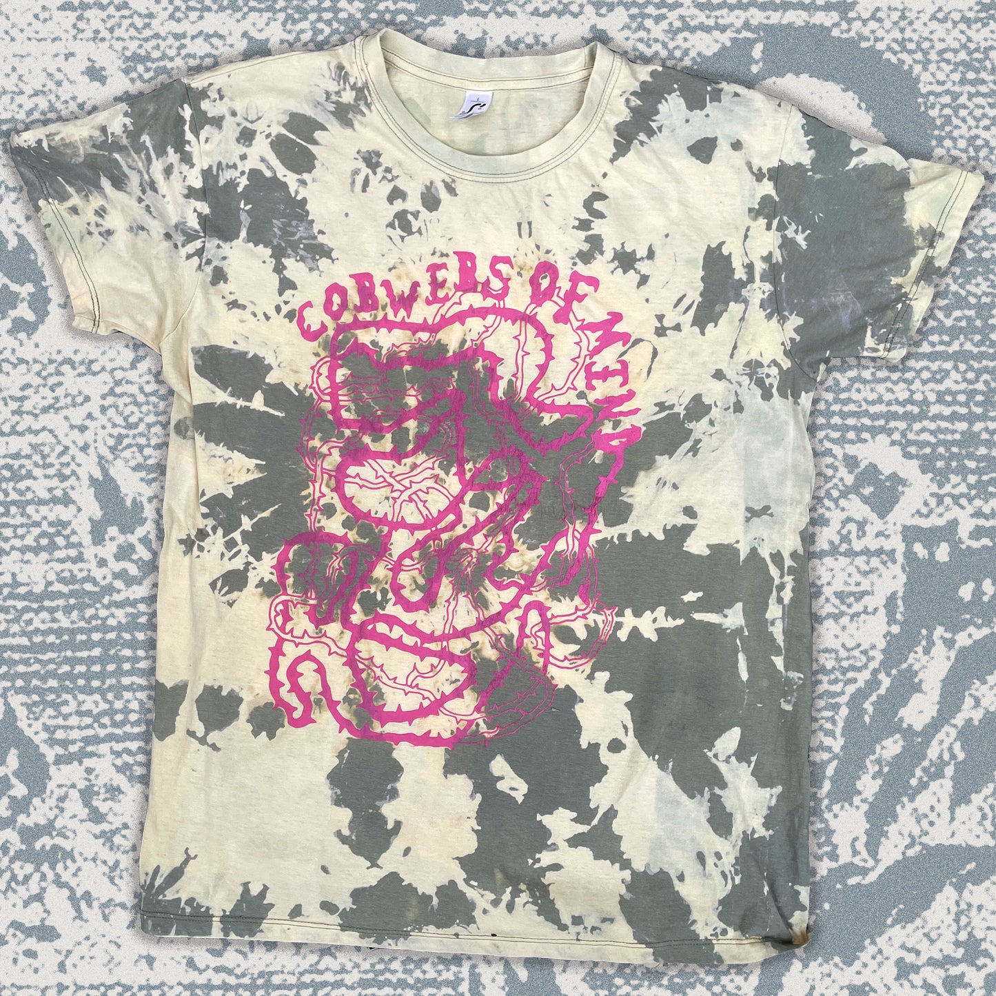 Bleached t-shirt with pink graphic design on a textured surface
