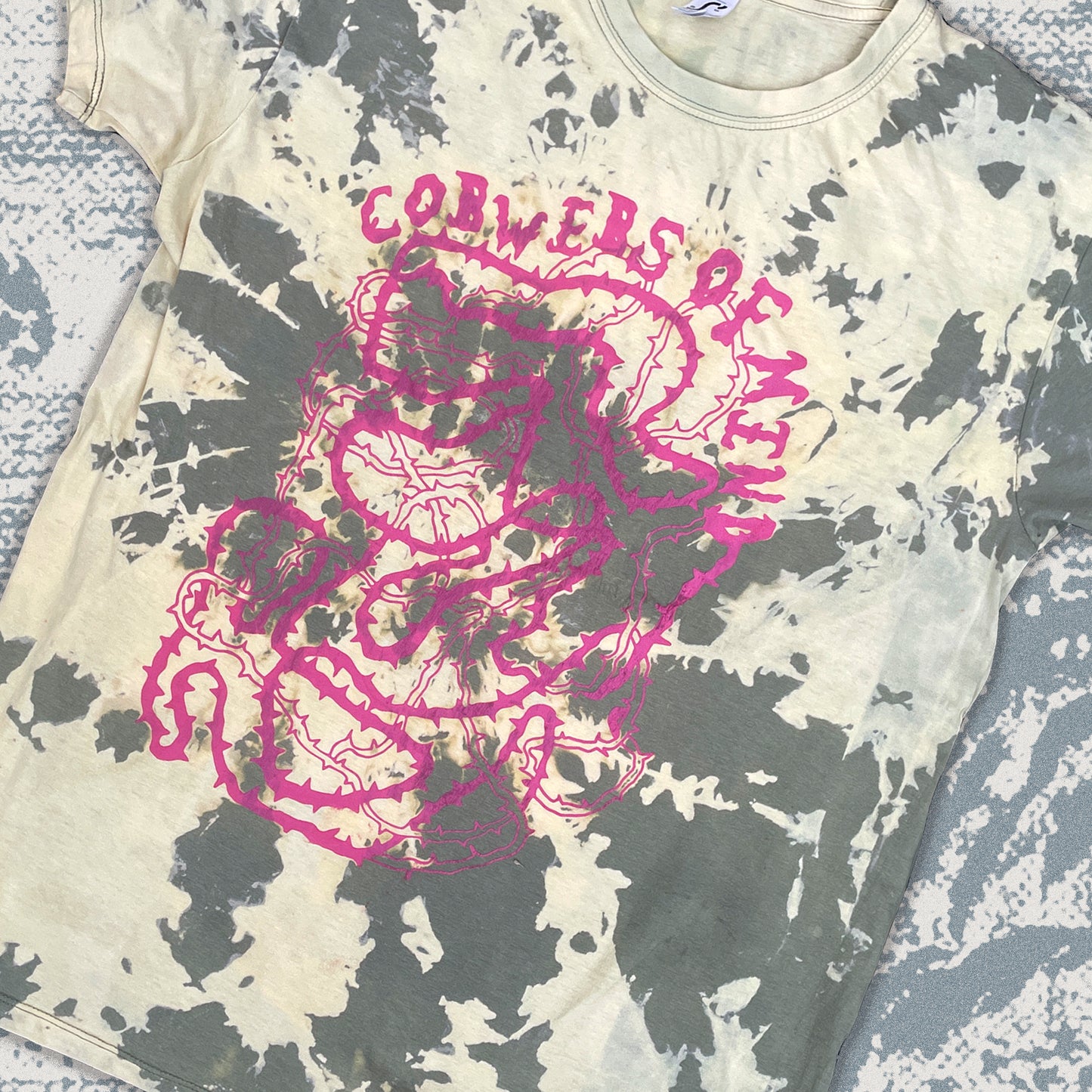 T-shirt with pink graphic design and text on a textured surface