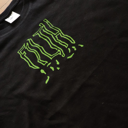 Close-up view of black t-shirt, FILTH is screen printed with neon green ink.