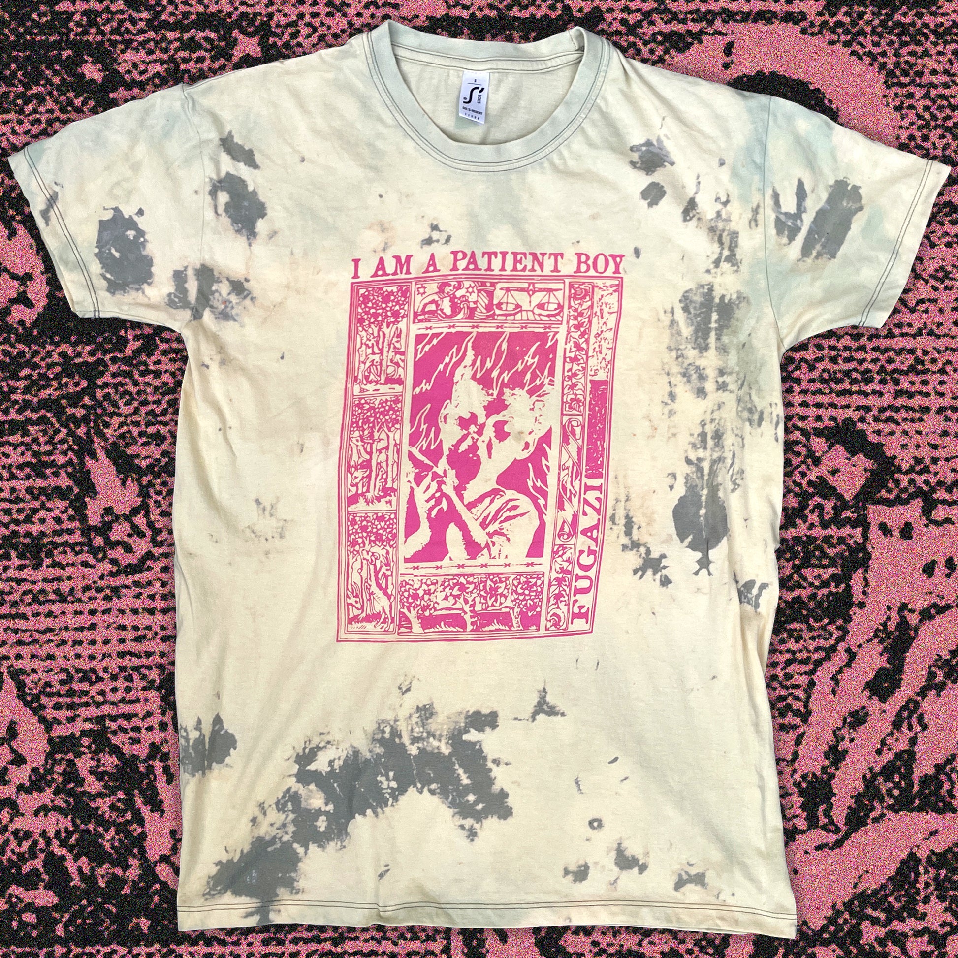 Bleached tie-dye T-shirt in soft cream with scattered gray distress patterns, hand screen printed in bright pink ink with a bold graphic design inspired by Fugazi.Each shirt has unique bleach markings for a one-of-a-kind, grunge look.