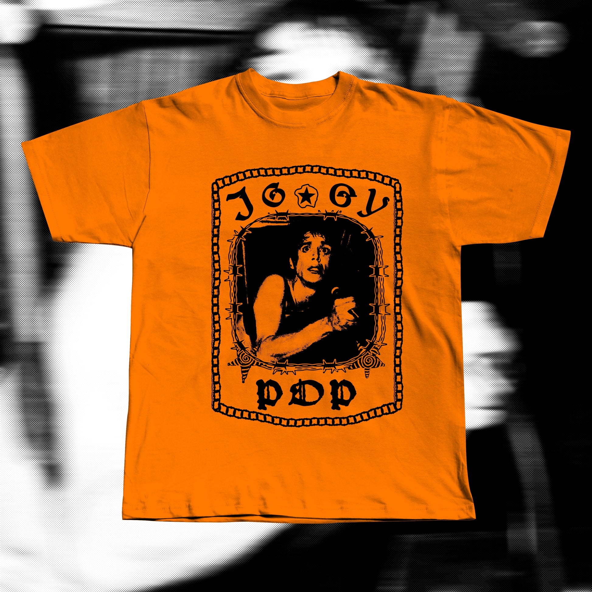 Unisex adult orange t-shirt, design with iggy pop tangled in a chair around barbed wire. Iggy pop is written around with gothic letters.