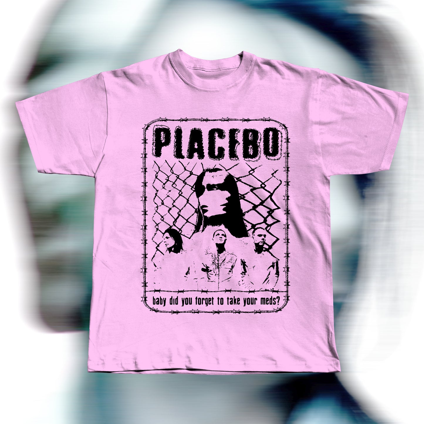 Handmade pink t-shirt featuring purple screen-printed fan art inspired by Placebo. The design shows the band members in front of a chain-link fence with “PLACEBO” written in bold distressed letters and the lyric “baby did you forget to take your meds?” below, surrounded by a barbed-wire border.
