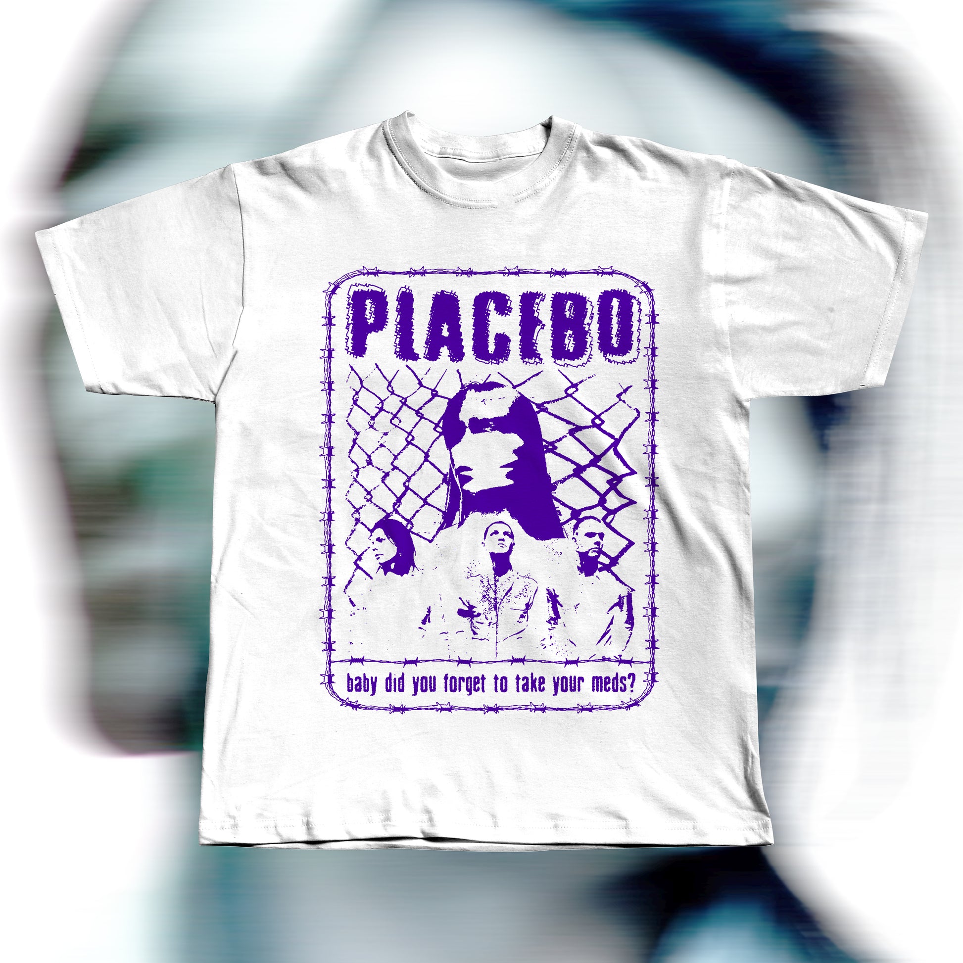 Handmade white t-shirt featuring purple screen-printed fan art inspired by Placebo. The design shows the band members in front of a chain-link fence with “PLACEBO” written in bold distressed letters and the lyric “baby did you forget to take your meds?” below, surrounded by a barbed-wire border.