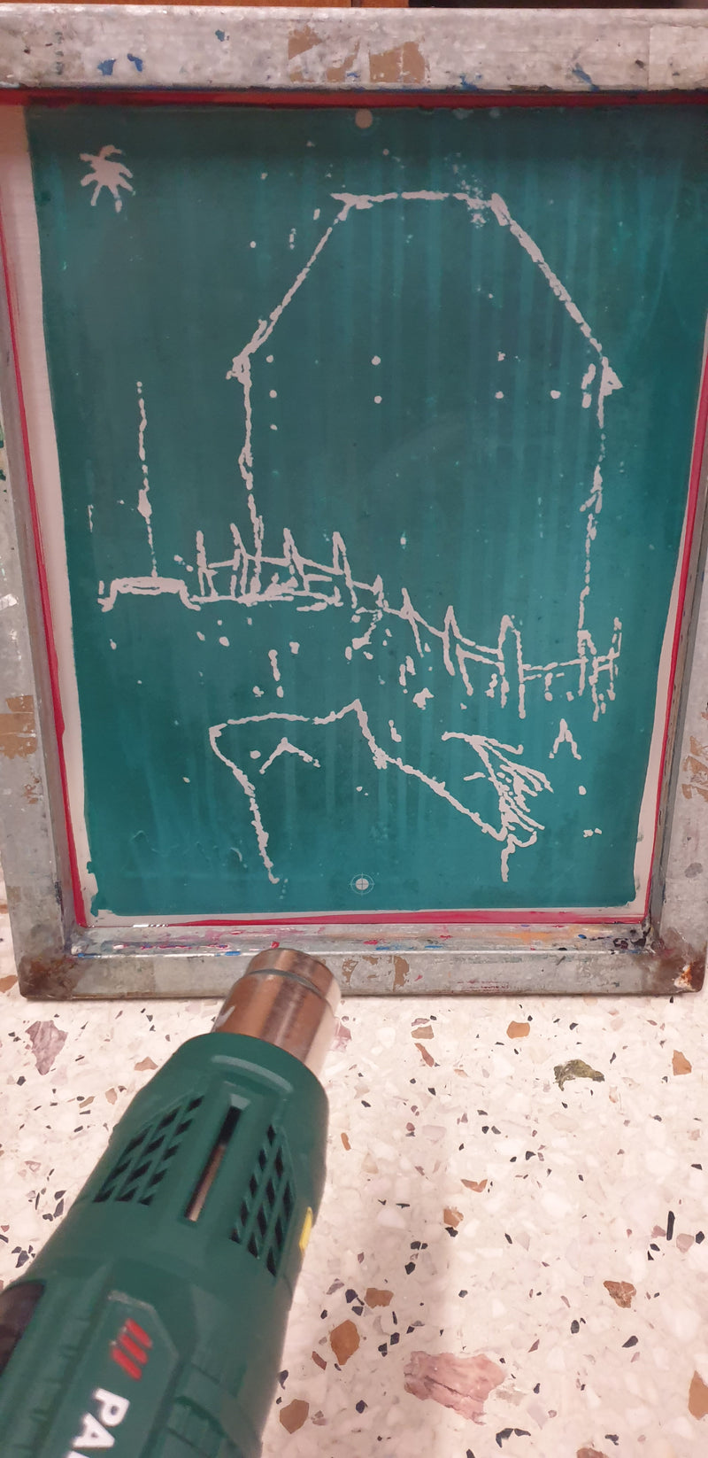 Hot air gun being used on a green chalkboard with white chalk drawings.