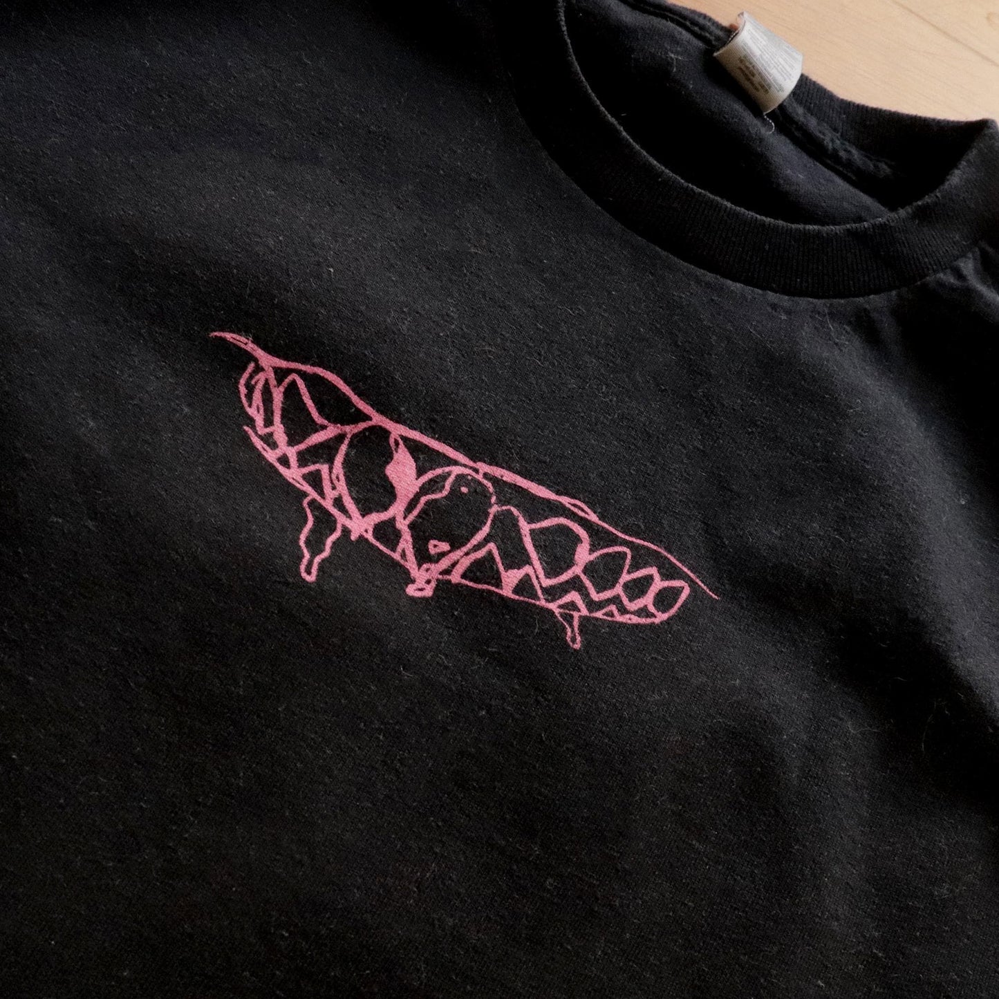 Close up view of the print in front. Teeth pink design on black heavy-cotton t-shirt.