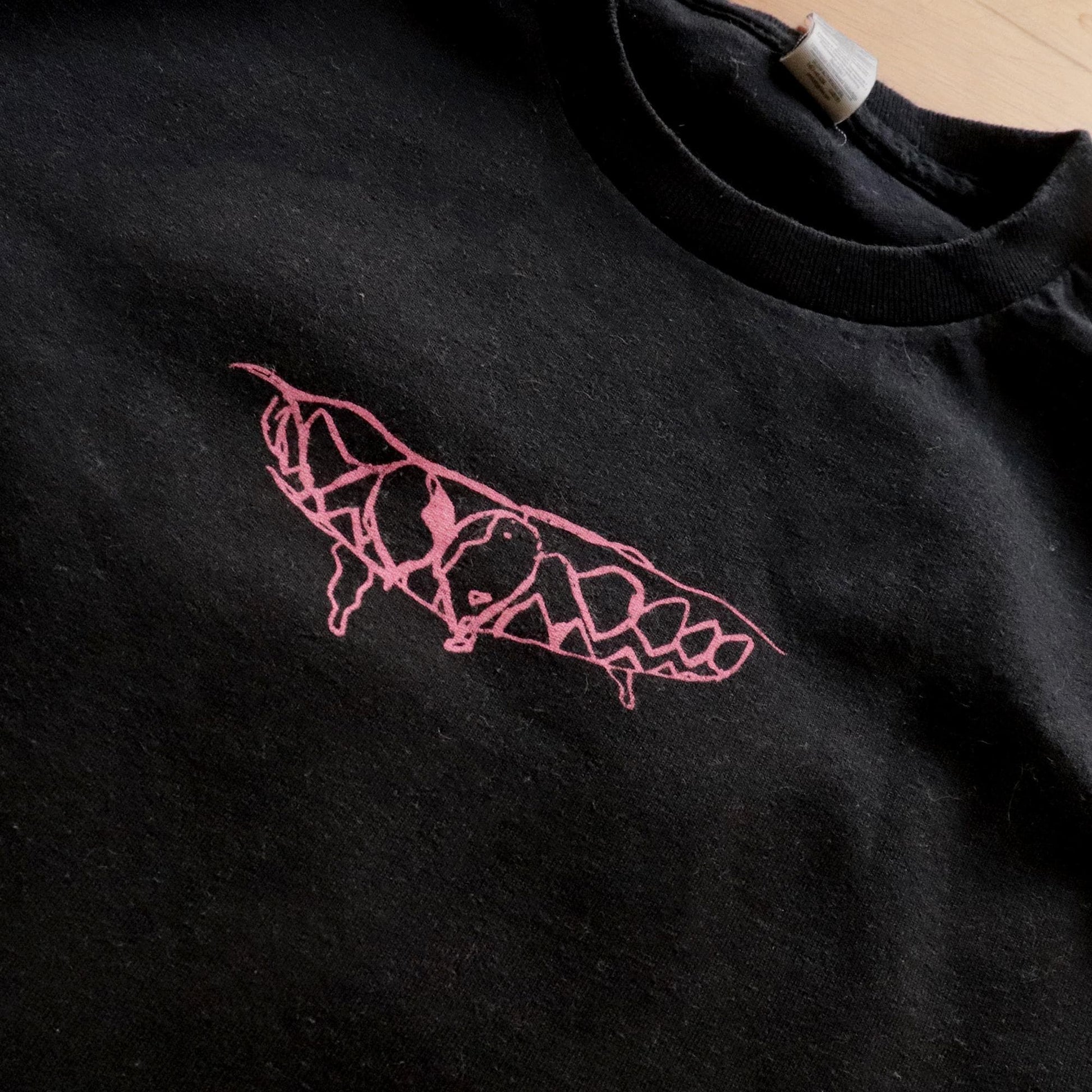 Close up view of the print in front. Teeth pink design on black heavy-cotton t-shirt.