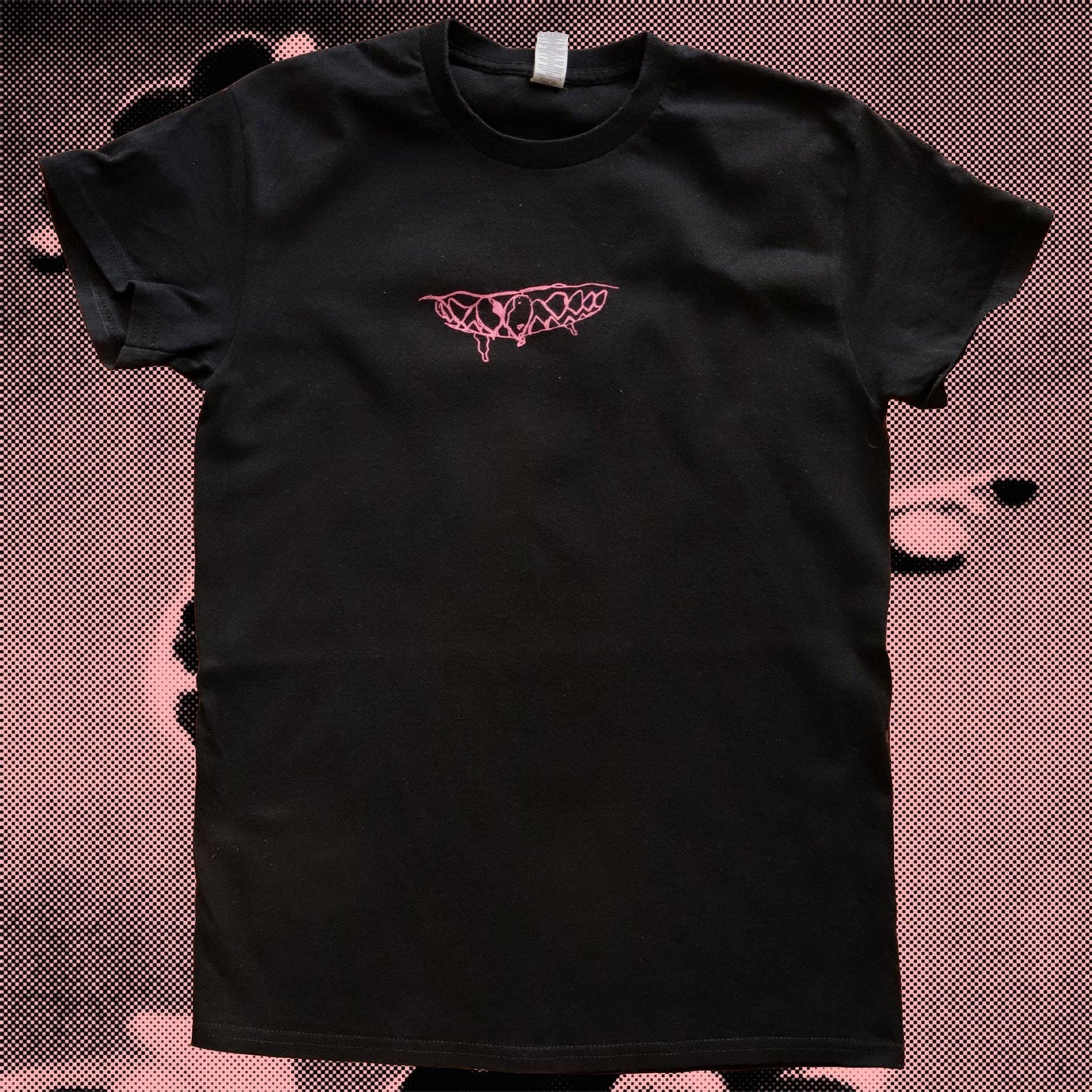 Black t-shirt with pink logo on a textured brown background