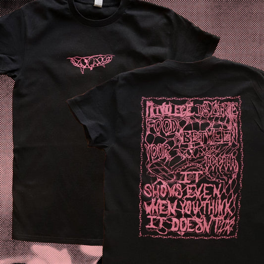 Black t-shirt with pink graphic design on a textured surface